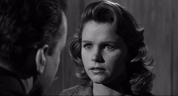 Movie still from “Anatomy of a Murder” (1959), directed by Otto Preminger – A young woman is looking at the camera while standing next to a man; Close Up shot, Over the shoulder angle