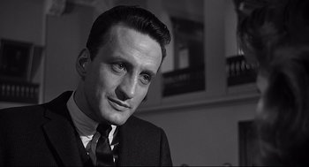 Movie still from “Anatomy of a Murder” (1959), directed by Otto Preminger – A black and white photo of a man wearing a suit and tie; Close Up shot, High angle