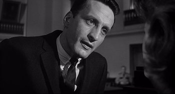 Movie still from “Anatomy of a Murder” (1959), directed by Otto Preminger – Black and white photograph of a man wearing a suit and tie; Close Up shot, Over the shoulder angle