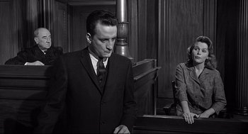 Movie still from “Anatomy of a Murder” (1959), directed by Otto Preminger – A man in a suit and tie standing in front of a judge; Medium shot, Low angle
