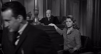 Movie still from “Anatomy of a Murder” (1959), directed by Otto Preminger – A woman is sitting in a courtroom with a judge; Medium shot, Over the shoulder angle