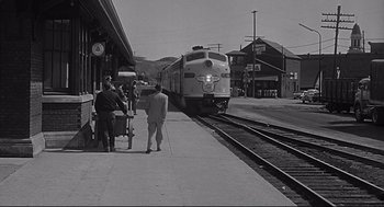 Movie still from “Anatomy of a Murder” (1959), directed by Otto Preminger – Two men standing on a train platform next to a train; Extreme Wide shot, Low angle