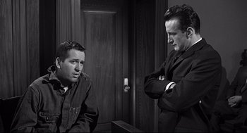 Movie still from “Anatomy of a Murder” (1959), directed by Otto Preminger – Two men are sitting next to each other in front of a wooden door; Medium shot, Low angle