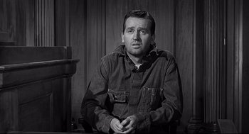 Movie still from “Anatomy of a Murder” (1959), directed by Otto Preminger – A black and white photo of a man sitting in a chair; Medium shot, Over the shoulder angle