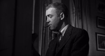Movie still from “Anatomy of a Murder” (1959), directed by Otto Preminger – A man in a suit smoking a pipe; Close Up shot, Low angle