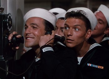 Movie still from “Anchors Aweigh” (1945), directed by Joseph Barbera – A group of men in navy uniforms talking on a phone; Medium shot, High angle