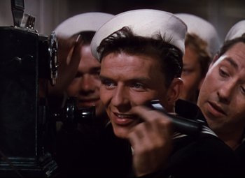 Movie still from “Anchors Aweigh” (1945), directed by Joseph Barbera – A group of men in uniform are looking at a camera; Medium shot, High angle