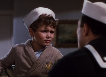 Movie still from “Anchors Aweigh” (1945), directed by Joseph Barbera – A young boy wearing a sailor's hat talking to another young man; Medium shot, Over the shoulder angle