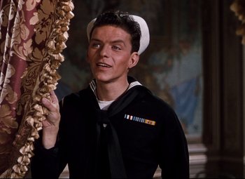 Movie still from “Anchors Aweigh” (1945), directed by Joseph Barbera – A man in a sailor's uniform holding a wreath; Medium shot, Over the shoulder angle