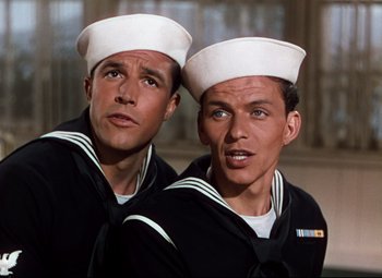 Movie still from “Anchors Aweigh” (1945), directed by Joseph Barbera – Two men in sailor's uniforms posing for a picture; Close Up shot, Low angle