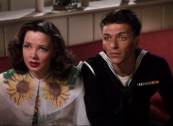 Movie still from “Anchors Aweigh” (1945), directed by Joseph Barbera – A man and a woman posing for a picture; Medium shot, High angle