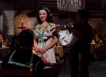 Movie still from “Anchors Aweigh” (1945), directed by Joseph Barbera – A woman in a dress holding a guitar and smiling; Medium shot, Over the shoulder angle