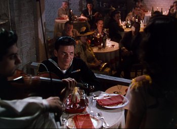 Movie still from “Anchors Aweigh” (1945), directed by Joseph Barbera – A group of people sitting at a table in a restaurant; Medium shot, Over the shoulder angle