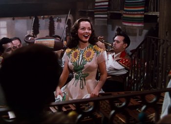 Movie still from “Anchors Aweigh” (1945), directed by Joseph Barbera – A woman wearing a dress with sunflowers on it and a man playing a violin; Medium shot, Low angle