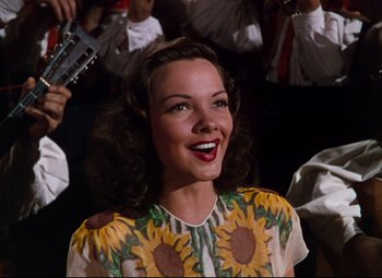 Movie still from “Anchors Aweigh” (1945), directed by Joseph Barbera – A woman in a sunflower dress smiling for the camera; Medium shot, Low angle