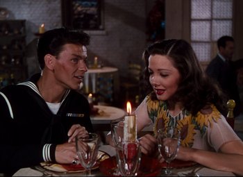 Movie still from “Anchors Aweigh” (1945), directed by Joseph Barbera – A man and a woman sitting at a dinner table; Medium shot, Over the shoulder angle