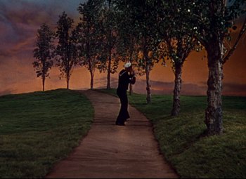 Movie still from “Anchors Aweigh” (1945), directed by Joseph Barbera – A man in a black suit is walking down a path at dusk; Extreme Wide shot, Low angle