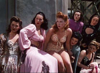 Movie still from “Anchors Aweigh” (1945), directed by Joseph Barbera – A group of women sitting next to each other on the ground; Medium shot, Low angle