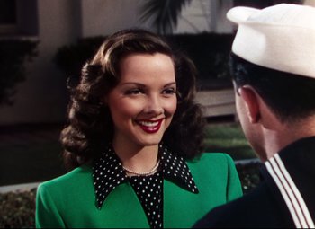 Movie still from “Anchors Aweigh” (1945), directed by Joseph Barbera – A woman in a green dress and polka dot collar; Medium shot, Over the shoulder angle
