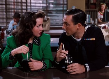 Movie still from “Anchors Aweigh” (1945), directed by Joseph Barbera – A man and a woman sitting at a table with drinks in front of them; Medium shot, Over the shoulder angle