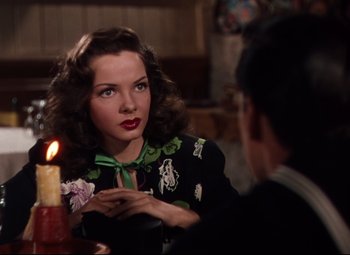 Movie still from “Anchors Aweigh” (1945), directed by Joseph Barbera – A woman sitting at a table with a lit candle; Close Up shot, Over the shoulder angle