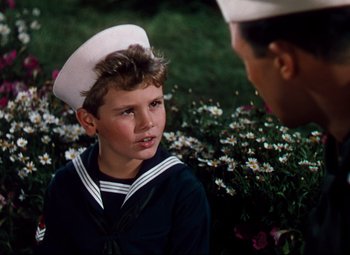 Movie still from “Anchors Aweigh” (1945), directed by Joseph Barbera – A young boy wearing a sailor's hat talking to an older man in a field of flowers; Close Up shot, High angle