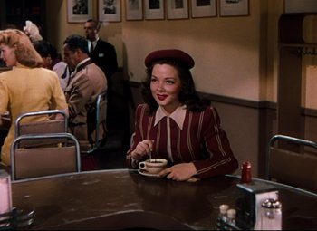 Movie still from “Anchors Aweigh” (1945), directed by Joseph Barbera – A woman sitting at a table with a cup of coffee; Medium shot, High angle
