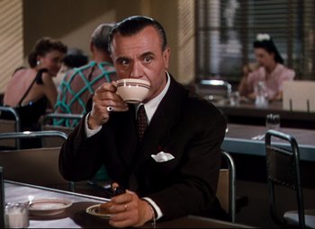 Movie still from “Anchors Aweigh” (1945), directed by Joseph Barbera – A man sitting at a table drinking a cup of coffee; Medium shot, Low angle