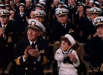 Movie still from “Anchors Aweigh” (1945), directed by Joseph Barbera – A group of people in uniform clapping in front of a crowd; Medium shot, High angle