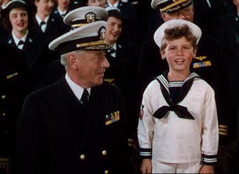 Movie still from “Anchors Aweigh” (1945), directed by Joseph Barbera – A group of people in uniforms and hats standing next to each other; Medium shot, High angle
