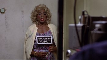 Movie still from “And Justice for All” (1979), directed by Norman Jewison – A woman holding a police department sign in front of a mirror; Close Up shot, Over the shoulder angle