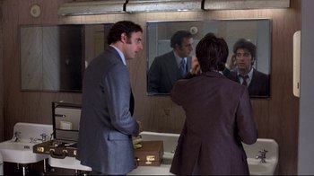 Movie still from “And Justice for All” (1979), directed by Norman Jewison – A man in a suit and tie in front of a bathroom mirror; Medium shot, Over the shoulder angle