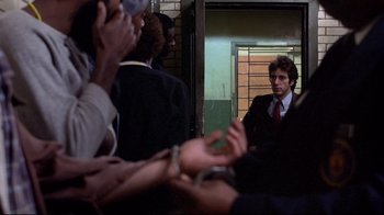 Movie still from “And Justice for All” (1979), directed by Norman Jewison – A man in a suit and tie standing in front of a group of people; Medium shot, Over the shoulder angle
