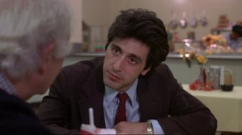 Movie still from “And Justice for All” (1979), directed by Norman Jewison – A man sitting at a table with a drink in front of him; Close Up shot, Over the shoulder angle