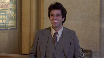 Movie still from “And Justice for All” (1979), directed by Norman Jewison – A man in a suit and tie smiling for the camera; Medium shot, Over the shoulder angle
