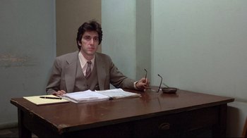 Movie still from “And Justice for All” (1979), directed by Norman Jewison – A man sitting at a desk in front of papers; Medium shot, Low angle