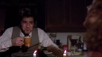 Movie still from “And Justice for All” (1979), directed by Norman Jewison – A man sitting at a dinner table holding a mug; Medium shot, Low angle