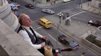 Movie still from “And Justice for All” (1979), directed by Norman Jewison – An older man sitting on the side of a building; Wide shot, Overhead angle