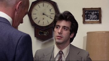 Movie still from “And Justice for All” (1979), directed by Norman Jewison – A man wearing a suit and tie in front of a clock; Close Up shot, Over the shoulder angle