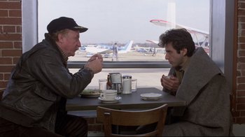 Movie still from “And Justice for All” (1979), directed by Norman Jewison – Two men are sitting at a table with food; Medium shot, Over the shoulder angle