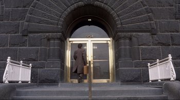 Movie still from “And Justice for All” (1979), directed by Norman Jewison – A man in a brown suit is entering a building; Extreme Wide shot, High angle