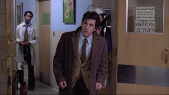 Movie still from “And Justice for All” (1979), directed by Norman Jewison – A man in a suit and tie standing next to another man; Medium shot, Over the shoulder angle