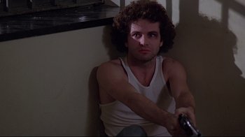 Movie still from “And Justice for All” (1979), directed by Norman Jewison – A man sitting on the ground holding a remote control; Close Up shot, Low angle