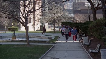 Movie still from “And Justice for All” (1979), directed by Norman Jewison – A group of people walking down a sidewalk near a park; Extreme Wide shot, High angle