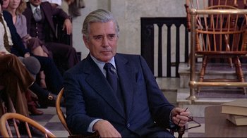 Movie still from “And Justice for All” (1979), directed by Norman Jewison – An older man in a suit and tie sitting in a chair; Medium shot, Over the shoulder angle