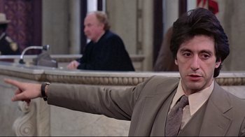 Movie still from “And Justice for All” (1979), directed by Norman Jewison – A man in a suit and tie sitting next to another man in a suit and tie; Medium shot, Low angle