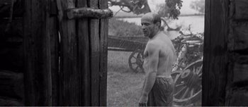 Movie still from “Andrei Rublev” (1966), directed by Andrei Tarkovsky – An old photo of a man standing in the rain; Medium shot, Over the shoulder angle