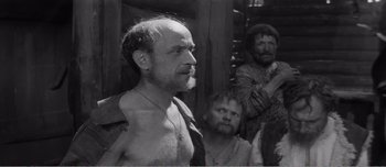 Movie still from “Andrei Rublev” (1966), directed by Andrei Tarkovsky – A black and white photo of a man with a beard; Medium shot, Over the shoulder angle