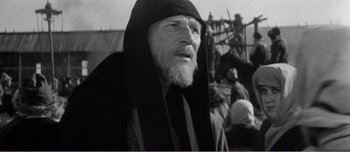 Movie still from “Andrei Rublev” (1966), directed by Andrei Tarkovsky – An old man with a beard wearing a hood; Close Up shot, Low angle