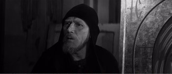 Movie still from “Andrei Rublev” (1966), directed by Andrei Tarkovsky – A man with a beard and a hood on; Close Up shot, High angle